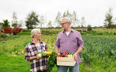 senior couple with box of vegetables on farm