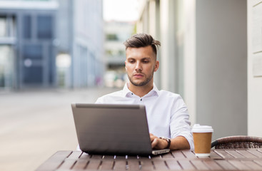 Fototapeta premium man with laptop and coffee at city cafe