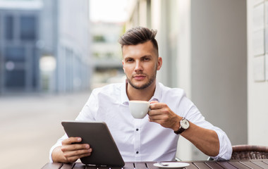 man with tablet pc and coffee at city cafe