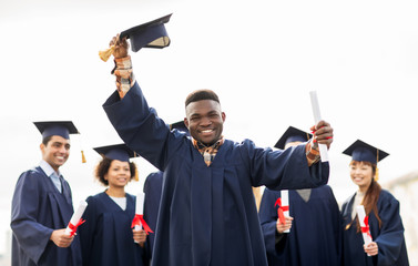 happy students in mortar boards with diplomas