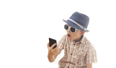 Caucasian kid with hat and sunglasses  holding smartphone  in his hand. Isolated on white background. Space for copy or other design.Astonished face