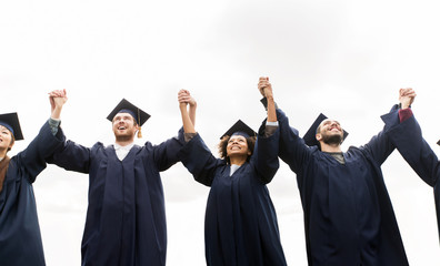 happy students or bachelors celebrating graduation