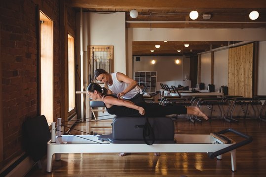 Trainer helping a woman while practicing pilates