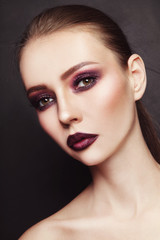 Fototapeta premium Portrait of young beautiful woman with stylish dark eyeshadow and lipstick