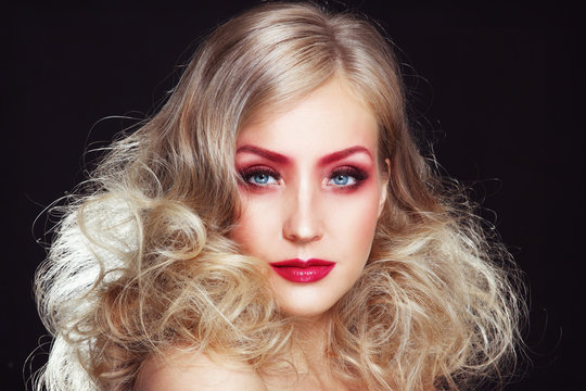 Portrait of young beautiful woman with stylish long curly hairdo and fancy red make-up