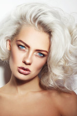 Portrait of young beautiful tanned woman with stylish make-up and platinum blonde curly hair