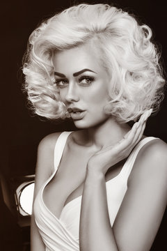 Vintage style black and white portrait of young beautiful glamorous woman with platinum blonde curly hair
