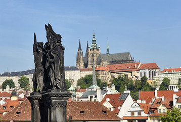 Fototapeta na wymiar Baroque Statues on the Charles Bridge with beautiful Prague Castle and St. Vitus Cathedral background. Focused to Prague Castle