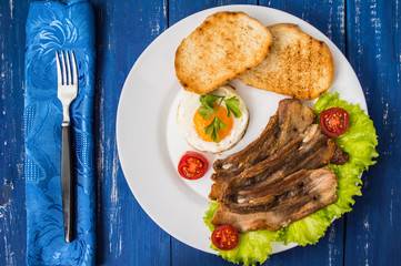 English breakfast - fried egg, tomatoes, bacon and toast. Top view