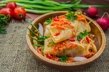 Cabbage rolls in tomato sauce in a bowl. wood background.