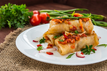 Cabbage rolls in tomato sauce. white plate. wood background.