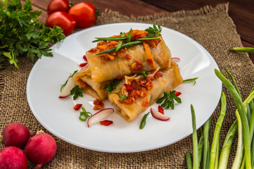 Cabbage rolls in tomato sauce. white plate. wood background.