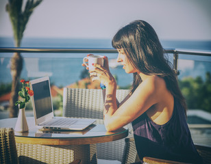 young woman with dark hair sitting at the table with a cup of co