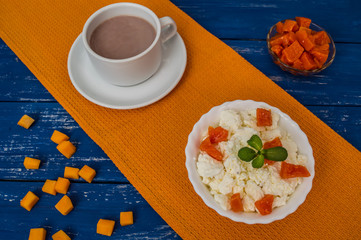 Breakfast from cottage cheese with pumpkin jam and cocoa on a blue wooden background. Top view