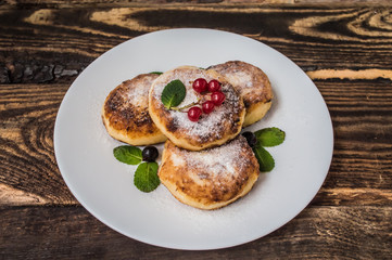 Cheesecakes with currants covered  powdered sugar on a wooden background. Top view