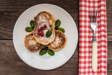 Cheesecakes with currants covered  powdered sugar on a wooden background. Top view