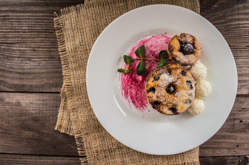 Cheesecakes with cherries and currants covered  powdered sugar on a wooden background. Top view