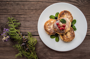 Cheesecakes with currants covered  powdered sugar on a wooden background. Top view