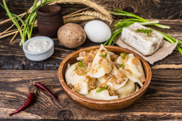 Boiled dumplings with potatoes. Wooden background. Top view