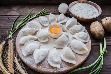 Raw dumplings with potatos on a wooden board. Rustic background