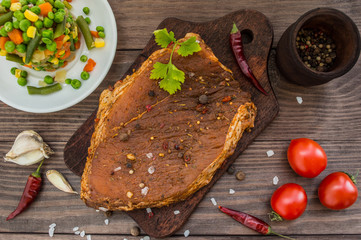 Marinated steak with spices on a wooden table