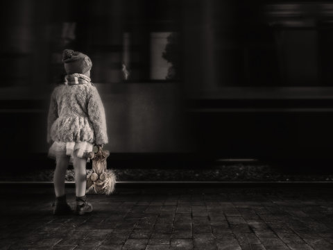 Bambina che aspetta in stazione con il suo orsacchiotto