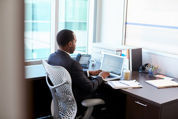 Doctor Working On Laptop At Desk In Office