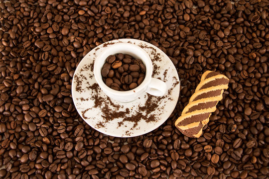 Espressotasse mit Keks umgeben von Kaffeebohnen 