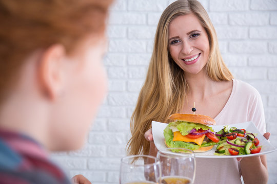 Woman holding cheeseburger with salad