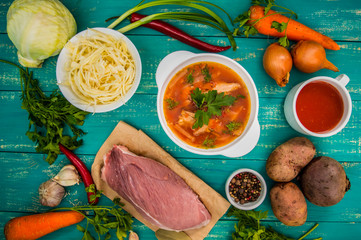 Traditional Ukrainian and Russian vegetable borsch on the turquoise wooden background. Top view. Close-up
