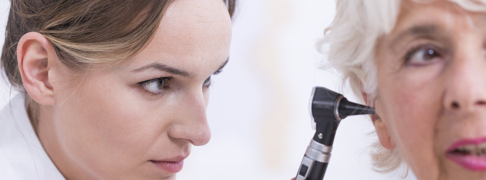 Doctor checking patient's ear with otoscope