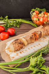 Pork cooked with vegetables on skewers  a wooden background