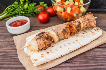 Pork cooked with vegetables on skewers  a wooden background