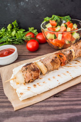 Pork cooked with vegetables on skewers  a wooden background