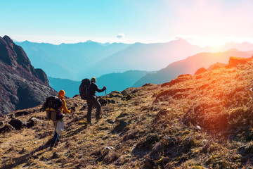 Obraz premium Hikers with Backpacks walking in Mountains towards rising Sun