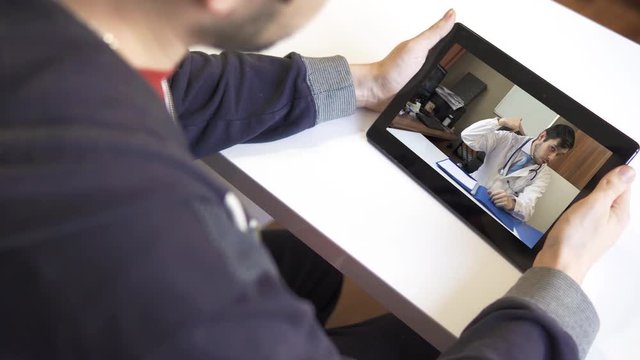 Patient holds tablet in hands and video chatting online with doctor.