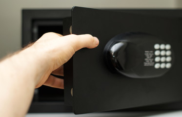Man's hand opening small safe.