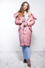 Beautiful curly girl in fashionable dress posing in the studio