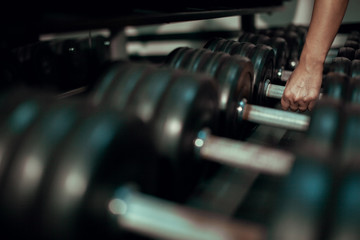 Fototapeta premium Young girl takes a dumbbell. Close up.