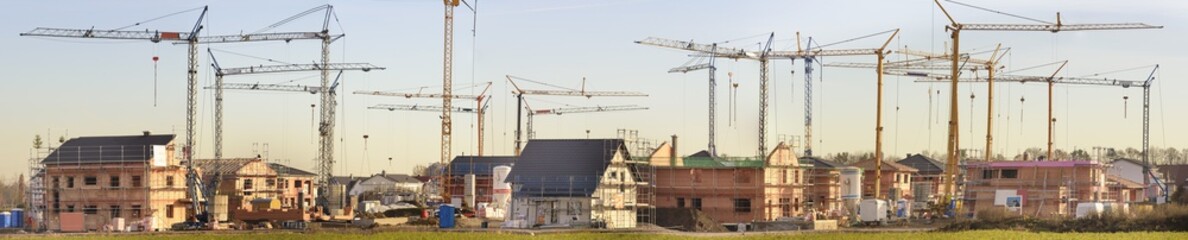 Panorama von Haus- und Wohnungsbau im Rohbau mit vielen Baukränen