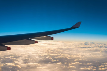 Wing of the air plane on the sea of cloud sunset sky background
