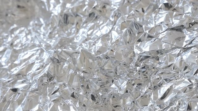 Slow tilt over food protection aluminium foil shiny texture 2160p 30fps UltraHD footage - Tin metal wrapping leaves for packing of goods 4K 3840X2160 UHD tilting video 