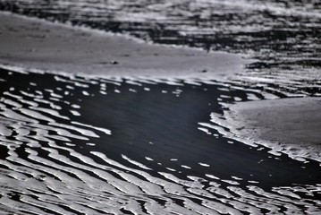 acqua e sabbia che formano strani disegni e colori in inverno sulla spiaggia a riva