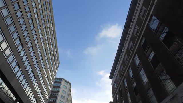 Looking up at tall office blocks from the city streets while moving along.