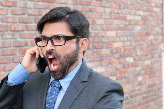 Stressed, young businessman screaming into phone 