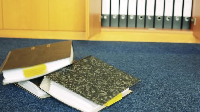 Woman throws with files with paper on carpet in office