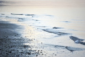 pennellate di azzurro sull'acqua del mare che con le onde si frange sulla spiaggia in inverno