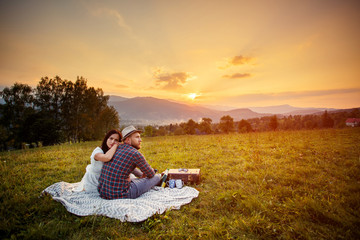 couple in love on white plaid. background mountains sunset