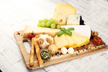 Cheese platter with different cheese and grapes - some emmental, gauda, parmesan and brie cheese on a table for brunch
