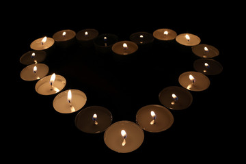 Small candles in the dark in heart shape